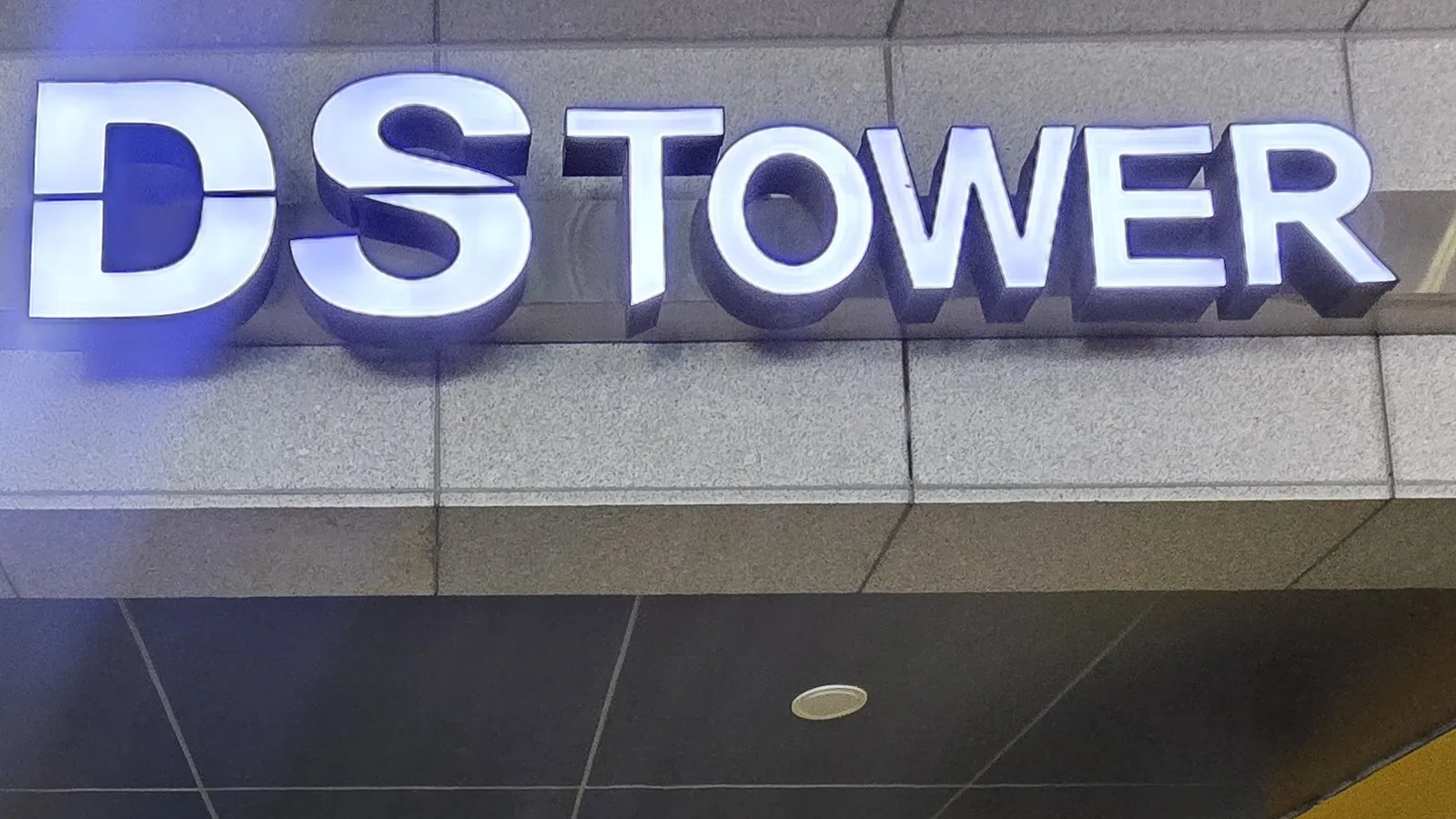 건물 입구 위에 불이 켜진 DS TOWER 간판